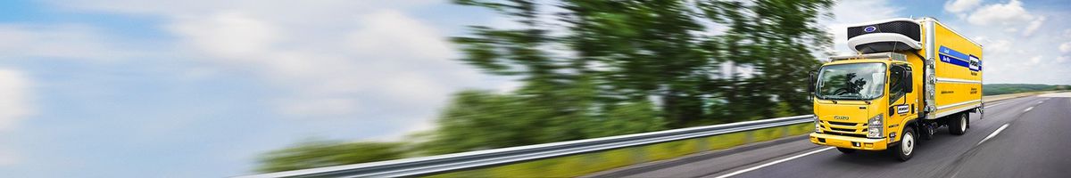 Penske cabover reefer truck driving on a tree-lined highway