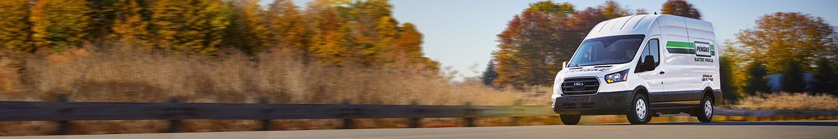 Penske electric cargo van driving on the highway surrounded by trees